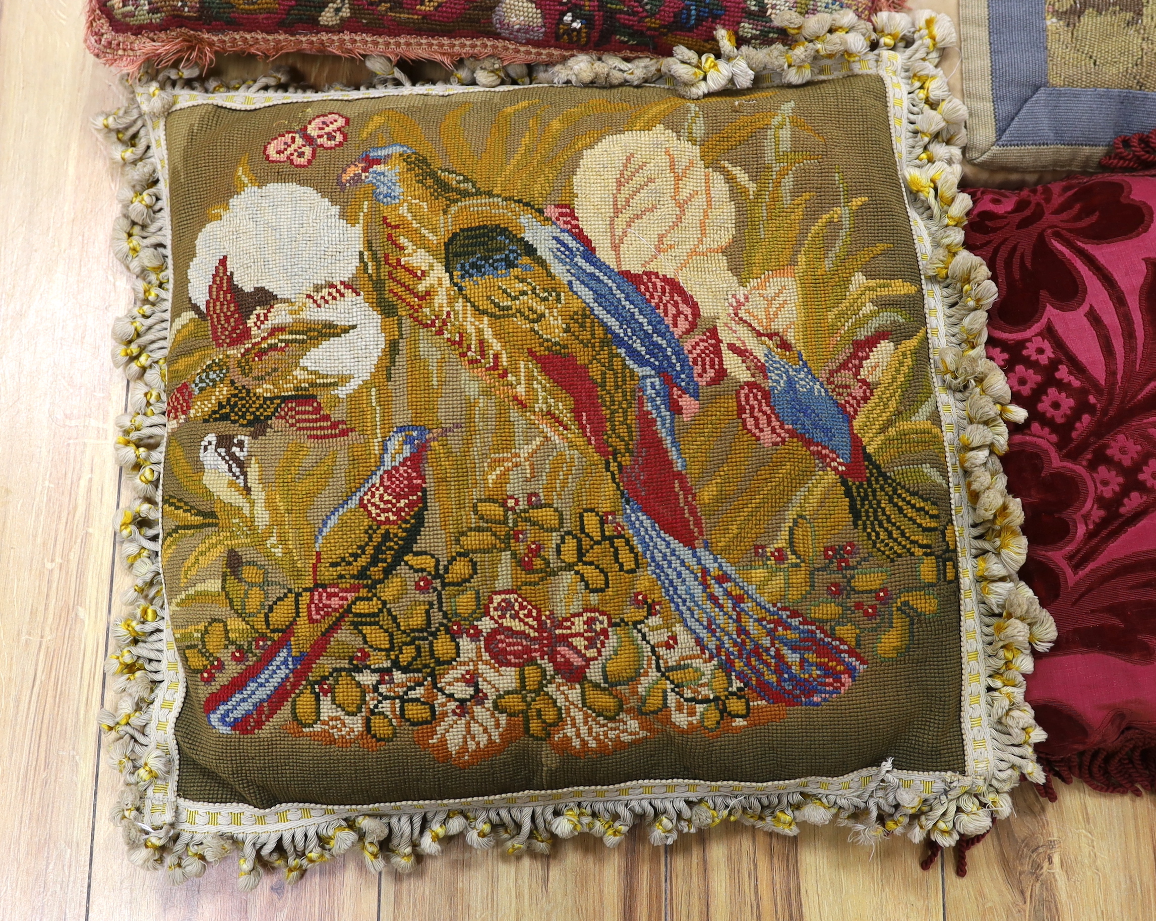 A late 18th century Flemish verdure tapestry fragment made into a cushion, a similar burgundy silk velvet damask cushion and two 19th early 20th century wool worked cushions (4)